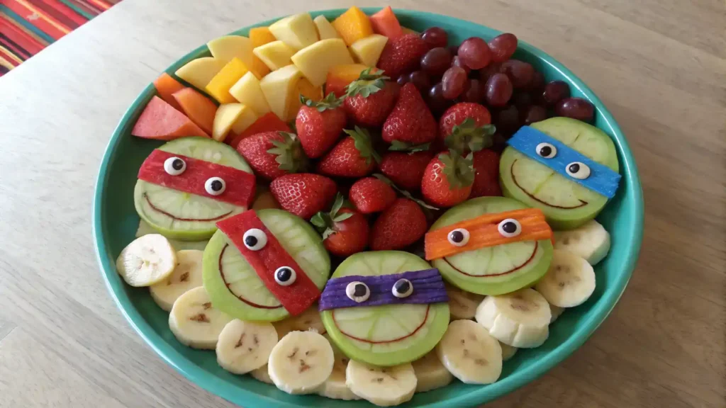 A vibrant TMNT fruit plate with fruits arranged as Ninja Turtle faces.
