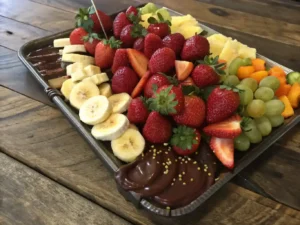 Delicious fruit and chocolate tray with strawberries, bananas, and grapes.