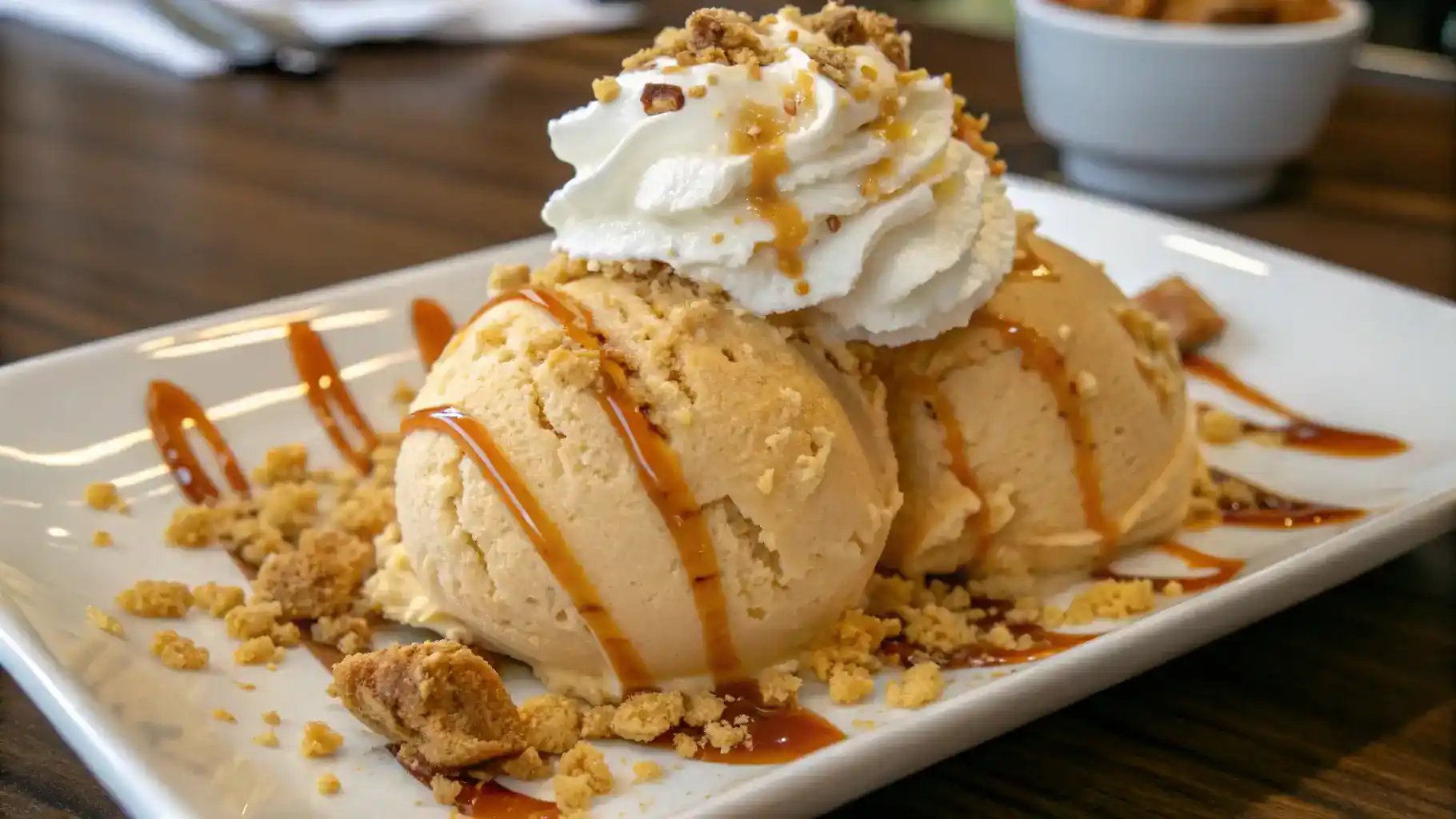 A beautifully plated caramel cheesecake ice cream dessert with caramel drizzle and whipped cream.